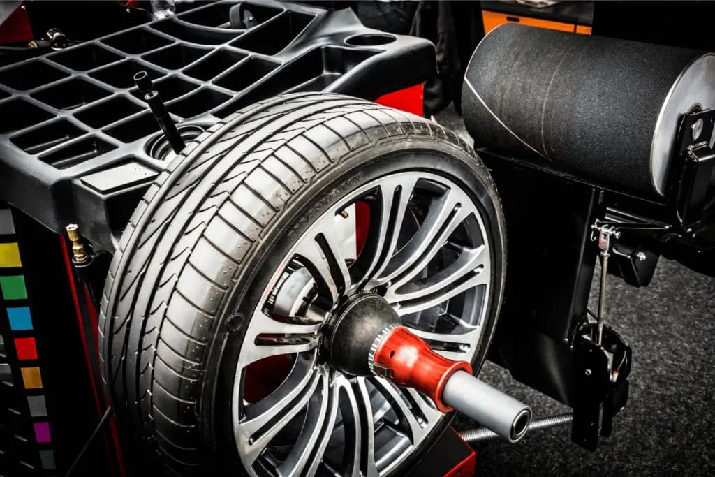 Wheel balancing machine spinning a car tire with precision in an automotive shop.